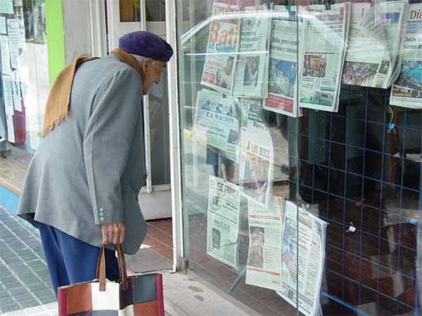 Homem olha jornais expostos em uma banca argentina