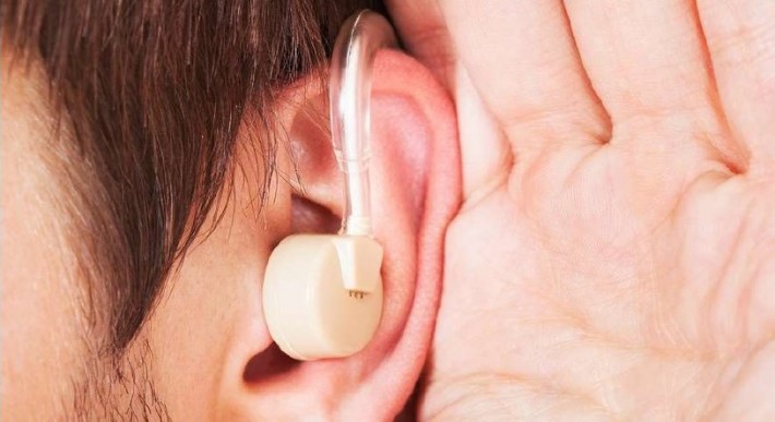 Foto com zoom muito aproximado de um aparelho auditiva encaixado em um ouvido.