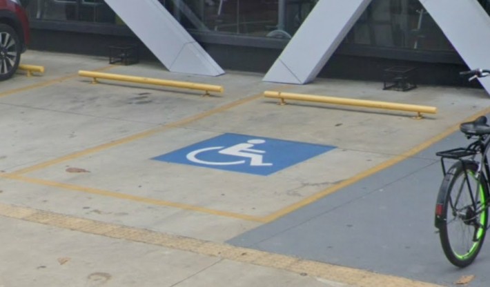 Foto de uma vaga reservada para pessoas com deficiência em um estacionamento aberto.