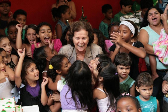 Foto da médica cardiologista Rosa Celia rodeada por crianças. Todos estão sorrindo. Crédito: Divulgação.