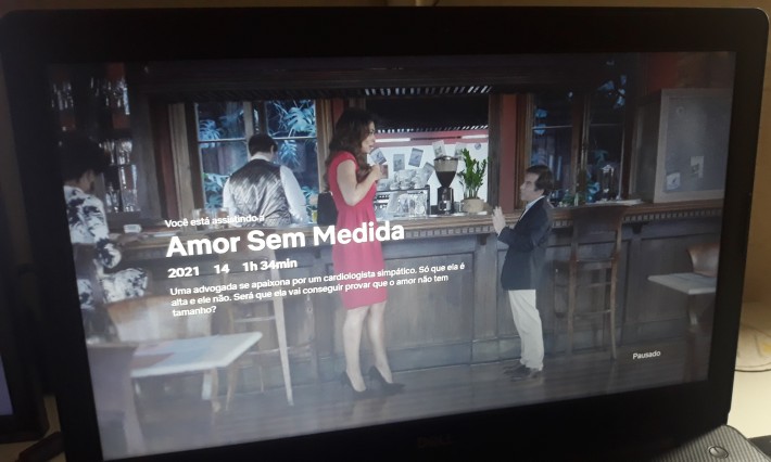 Foto de um notebook aberto com frame do longa 'Amor Sem Medida' que mostra o primeiro encontro das personagens de Juliana Paes e Leandro Hassum. Ela está espantada com a estatura dele.