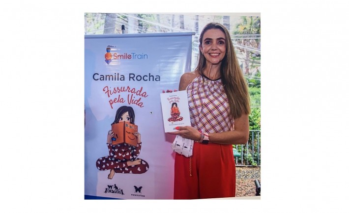 A escritura Camila Rocha, mulher branca de 30 anos, posa segurando o livro 'Fissurada pela Vida'.