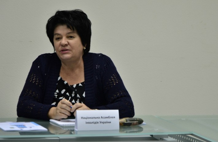 Foto de Larysa Bayda, mulher ucraniana de pele branca e cabelos pretos, curtos. Está sentada atrás de uma mesa, falando.