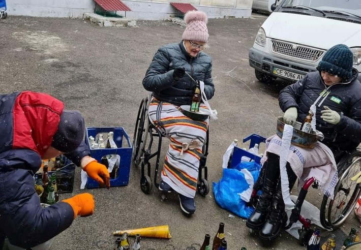 Foto de uma idosa e uma menina, ambas em cadeiras de rodas, montando as garrafas incendiárias em frente a um prédio.