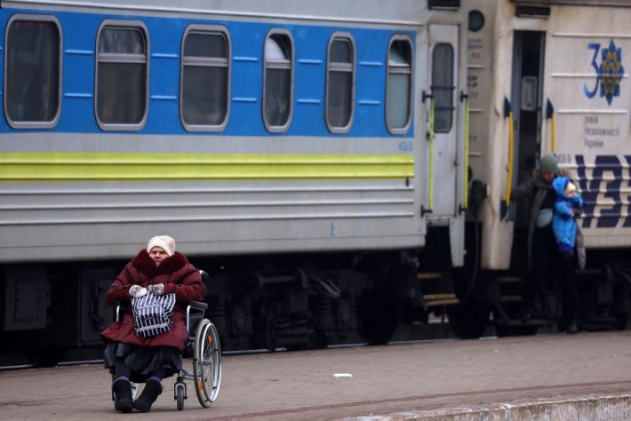 Foto de uma mulher em cadeira de rodas ao lado de um trem.