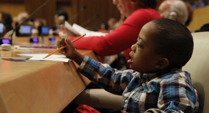 Foto de criança negra com síndrome de Down desenhando.