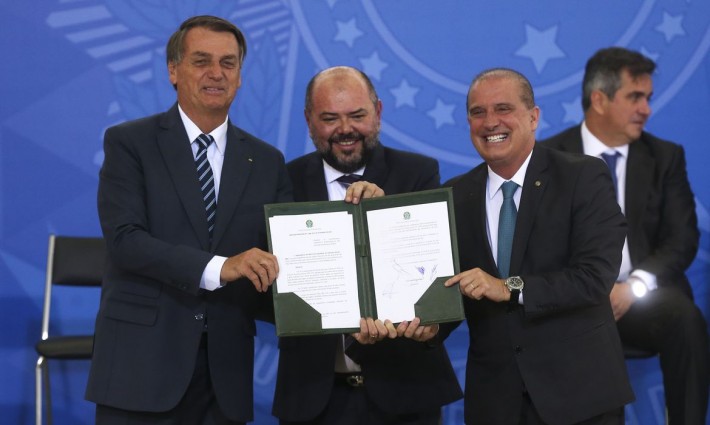 Foto de Jair Bolsonaro com o ministro José Carlos Oliveira, do Trabalho e Previdência, exibindo o decreto e a medida provisória que atualizam as normas do programa de aprendizagem profissional.