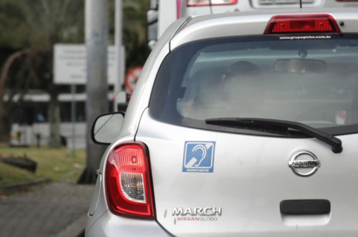 Foto da traseira de um carro com um colante que simboliza a deficiência auditiva.